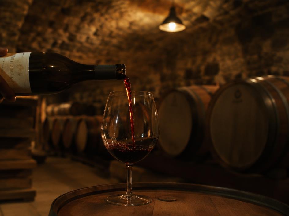 Red wine poured into a tasting glass in a barrel cellar