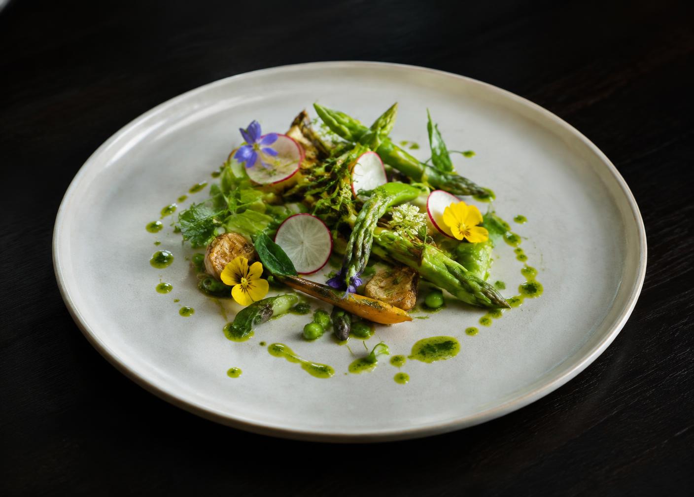Plate of garden vegetables, herbs and edible flowers on pale ceramic